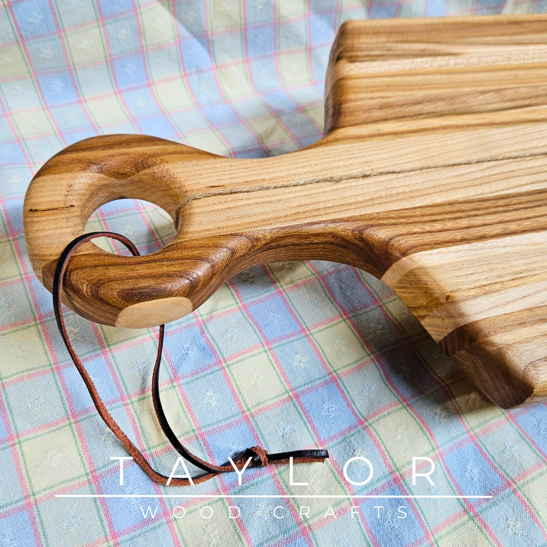 Handcrafted paddle board made from elm wood, featuring a leather string for hanging, offering durability and rustic charm.