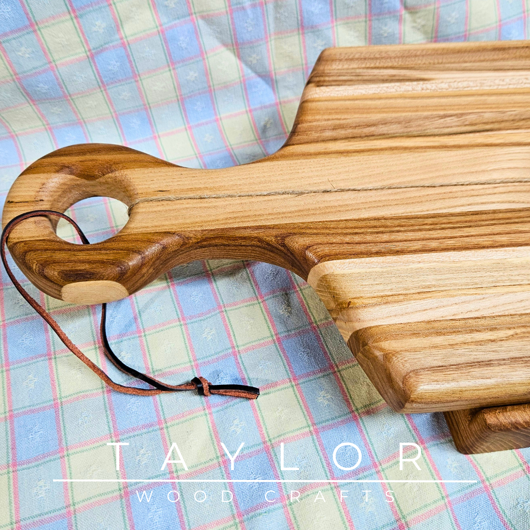 Handcrafted paddle board made from elm wood, featuring a leather string for hanging, offering durability and rustic charm.