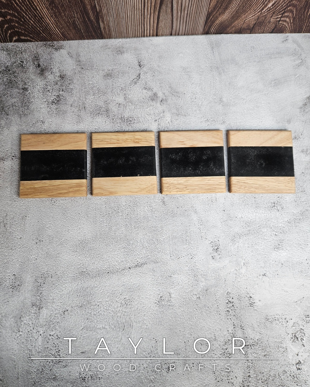 Four wooden cutting boards with black surfaces on a concrete surface, branded 'Taylor Woodcraft'.
