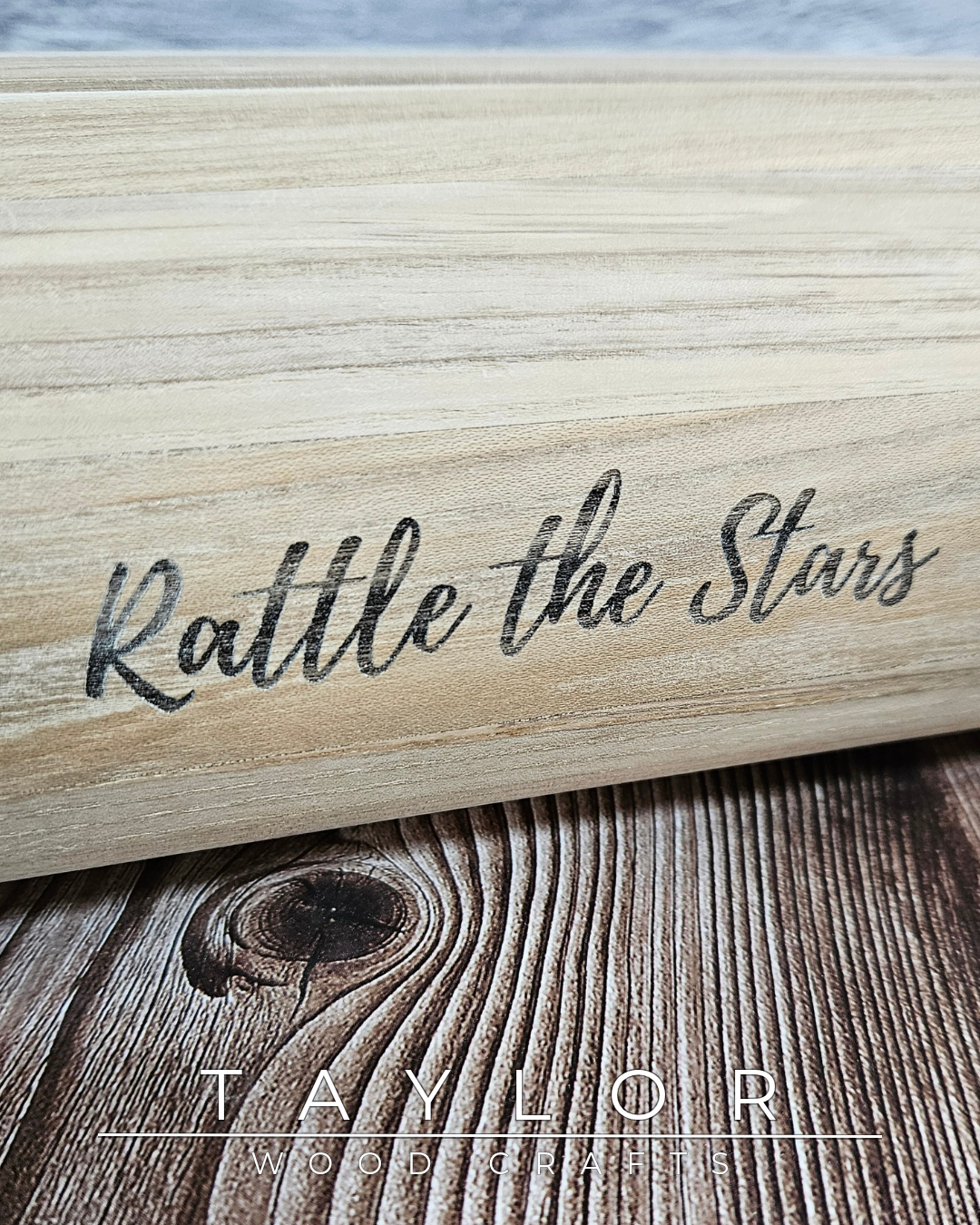 Wooden product with 'Rattle the Stars' engraved on it, placed on a wooden surface.