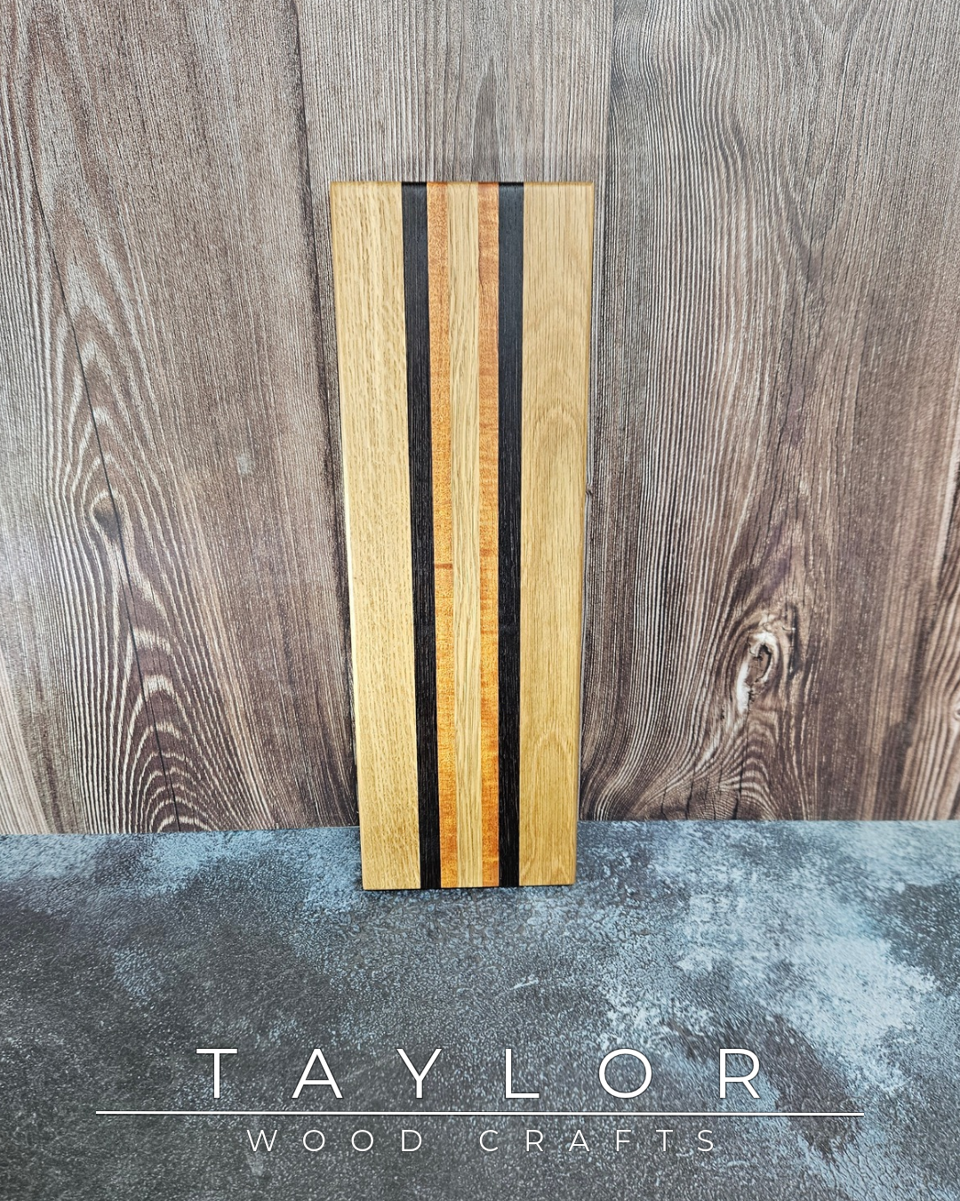 Wooden cutting board with black stripes on a wooden surface, branded 'Taylor Wood Crafts'.