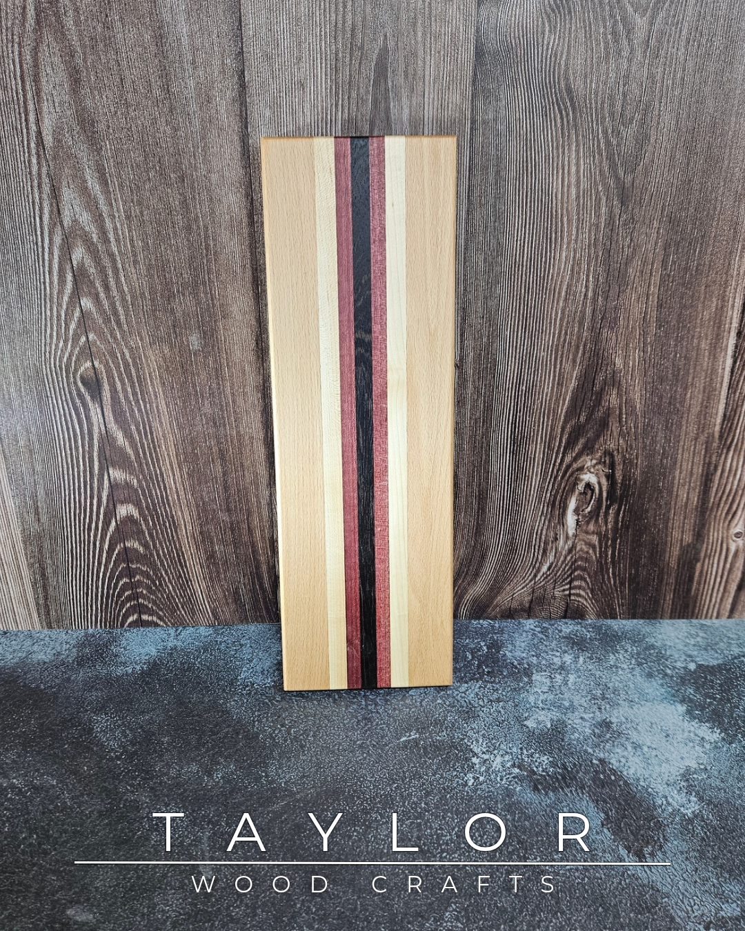 Wooden cutting board with multicolored stripes on a wooden background with 'Taylor Wood Crafts' branding.