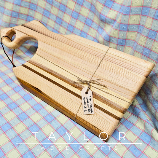 Handcrafted cleaver-shaped charcuterie board with a leather string for hanging, offering unique style and functionality for serving appetizers.