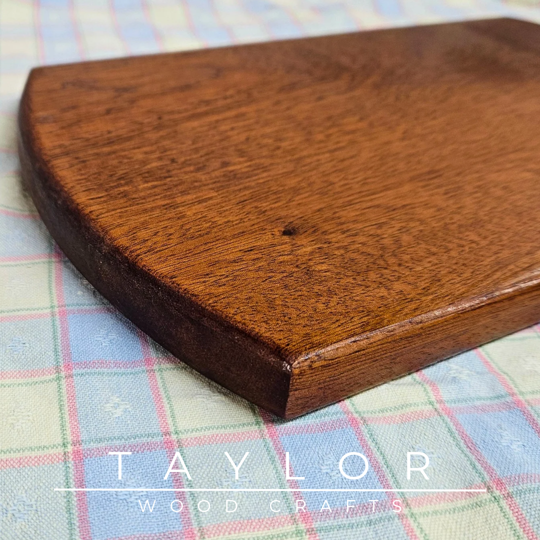 Handcrafted oval cherry wood charcuterie board, showcasing natural grain, perfect for serving appetizers or as a decorative piece.