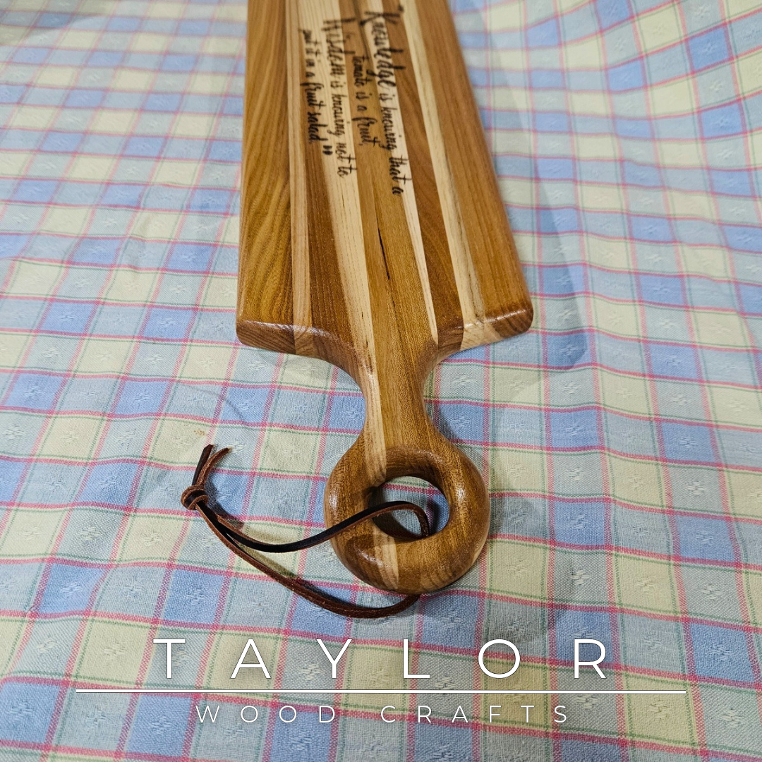 Handcrafted elm wood charcuterie board shaped like a paddle, showcasing rich wood grain for a rustic and elegant touch.
