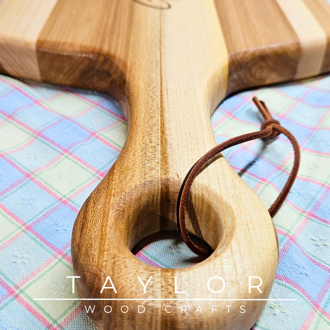 Handcrafted paddle board with a leather string for hanging, combining rustic charm and functionality for serving or display.