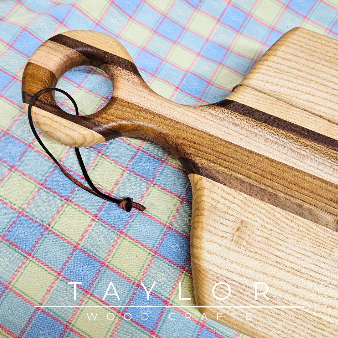 Handcrafted paddle board made with elm, ash, and walnut, featuring a leather string for hanging, combining durability and rustic style.