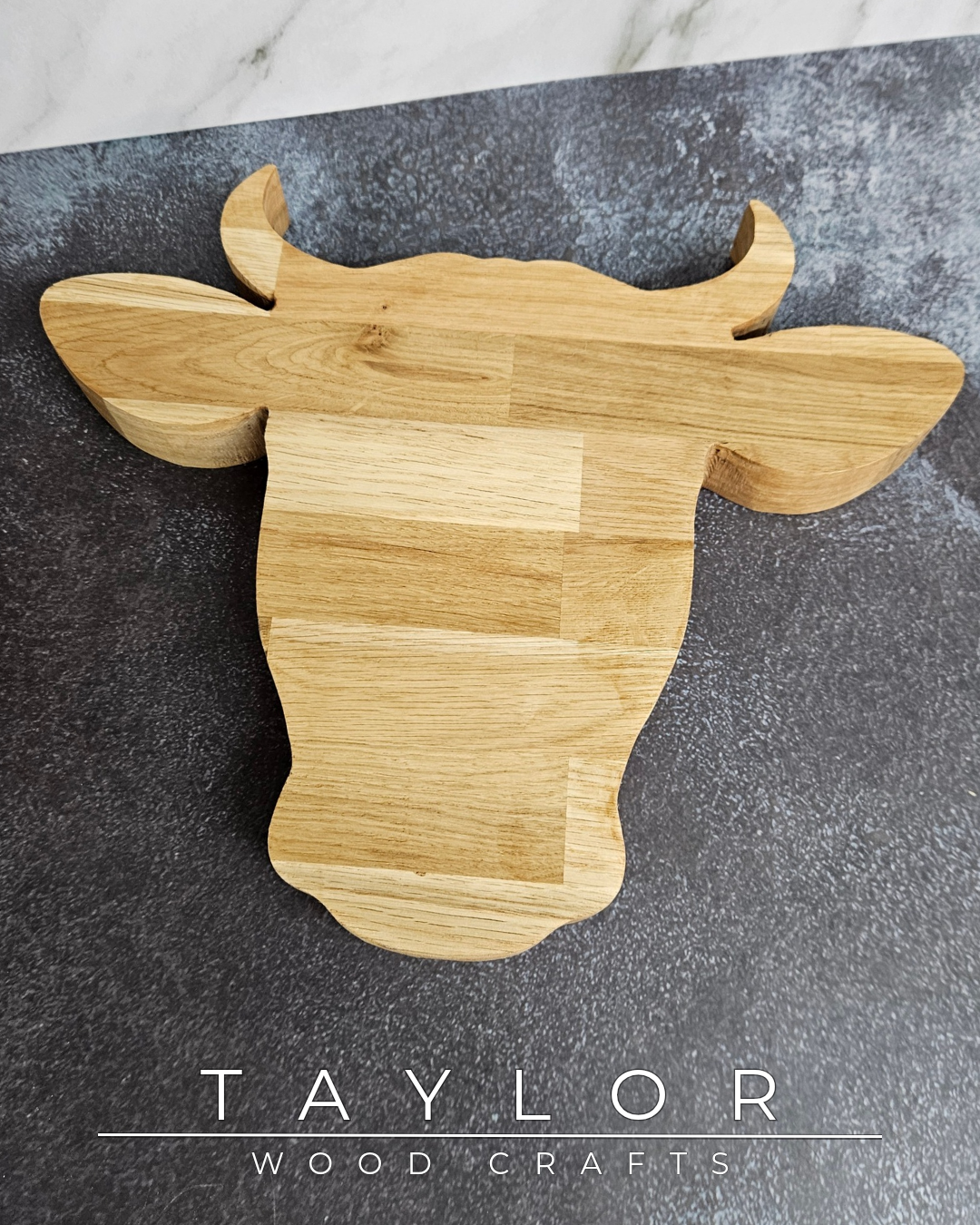 Wooden cow-shaped cutting board on a dark surface with 'Taylor Wood Crafts' branding.