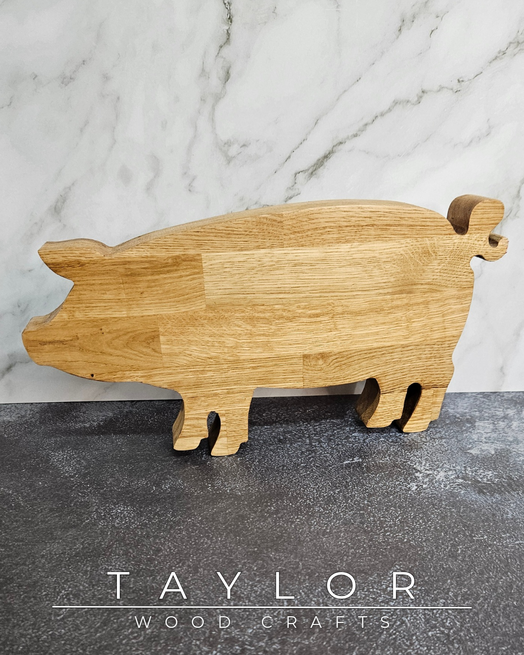 Wooden pig-shaped cutting board on a marble and slate surface with 'Taylor Wood Crafts' branding.
