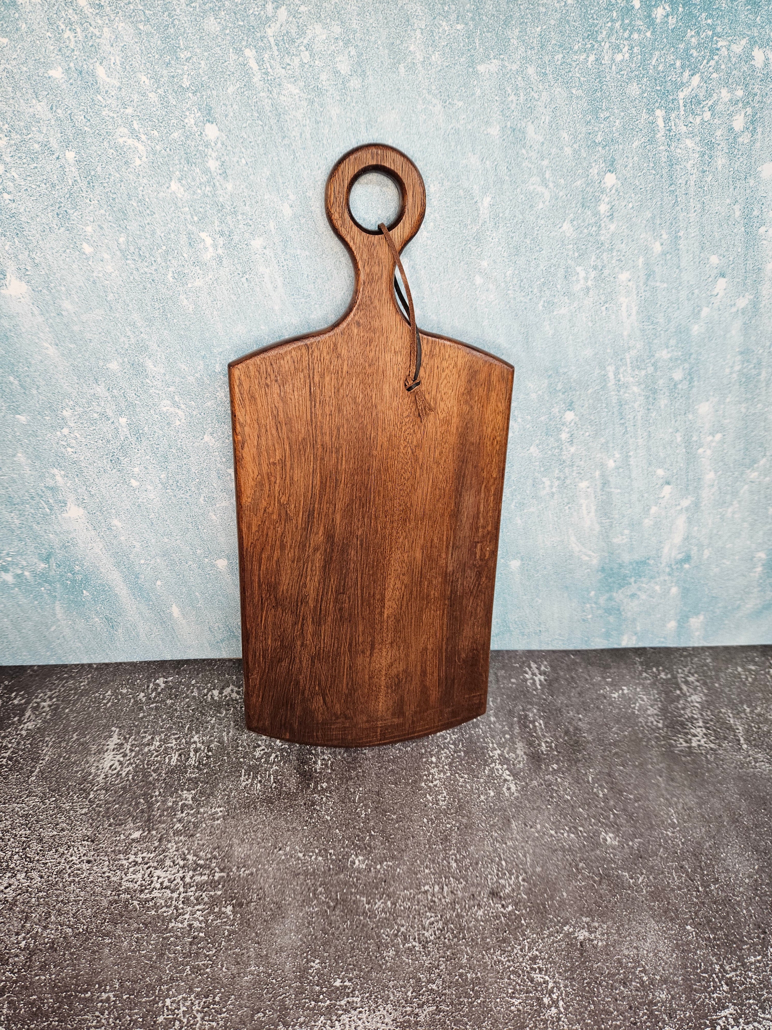Handcrafted cherry wood paddle board with a smooth, polished surface, highlighting natural grain, perfect as a functional or decorative piece.