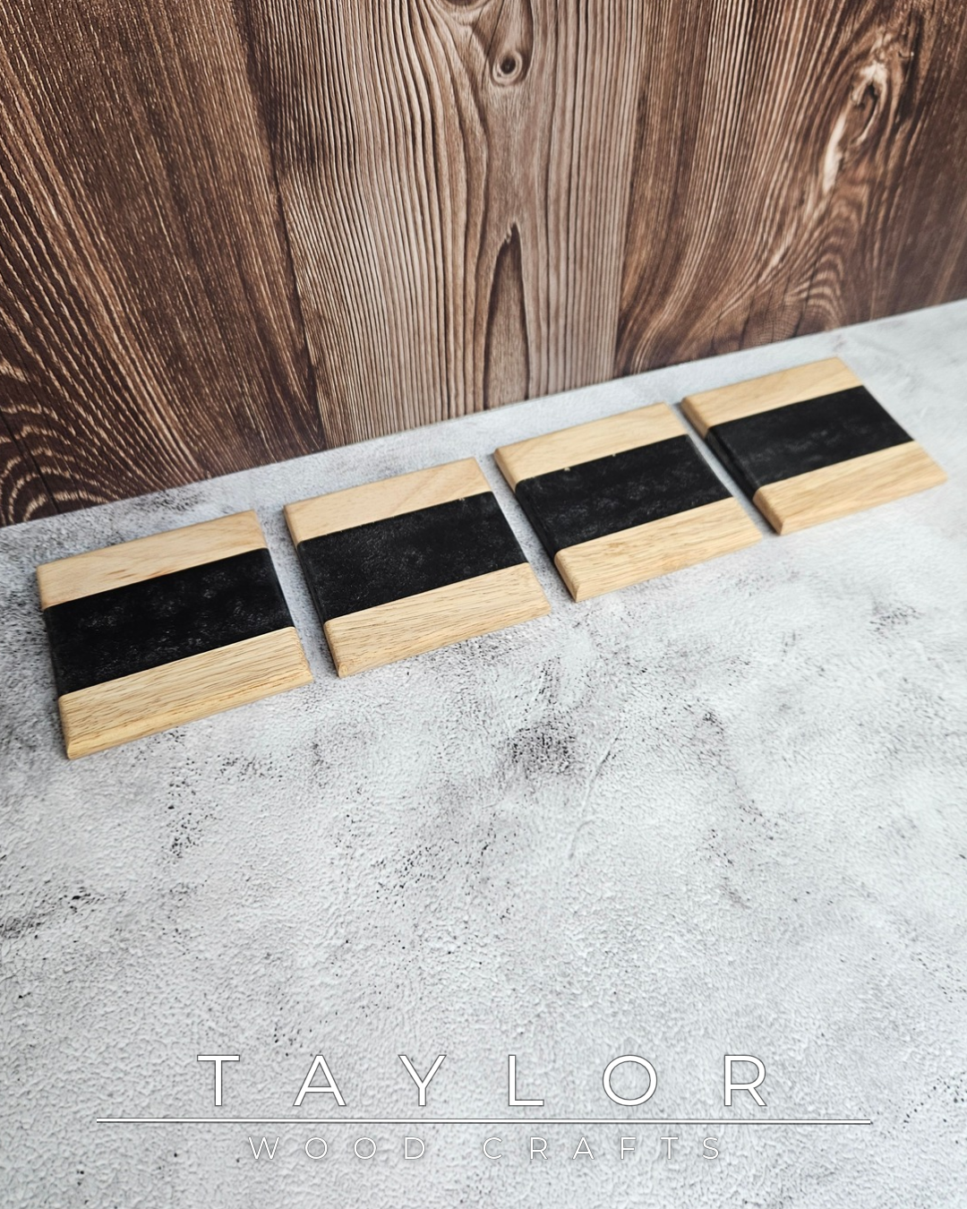 Set of wooden coasters with black rubber pads on a concrete surface, branded 'Taylor Wood'.