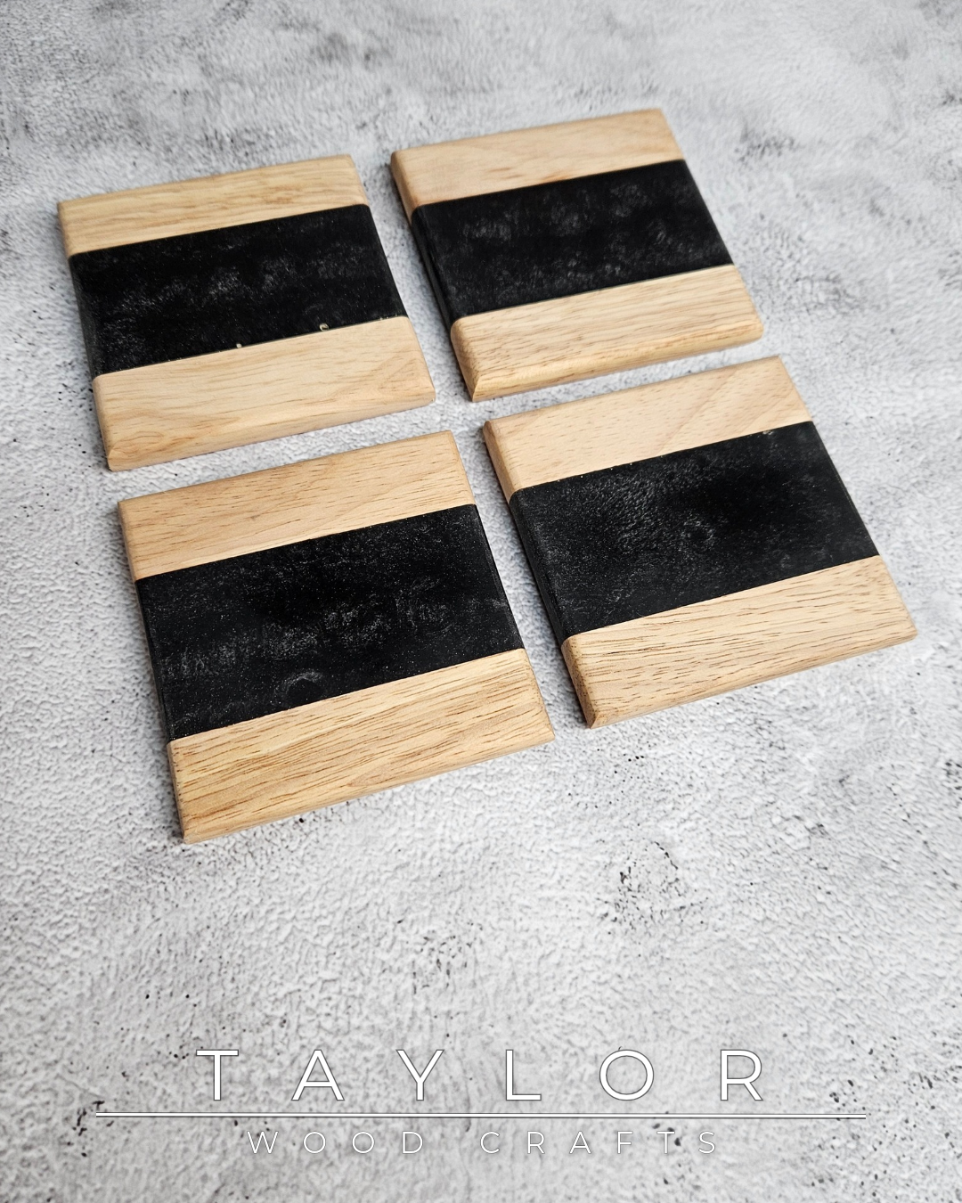 Four wooden coasters with black centers on a gray surface, branded 'Taylor Woodcraft'.