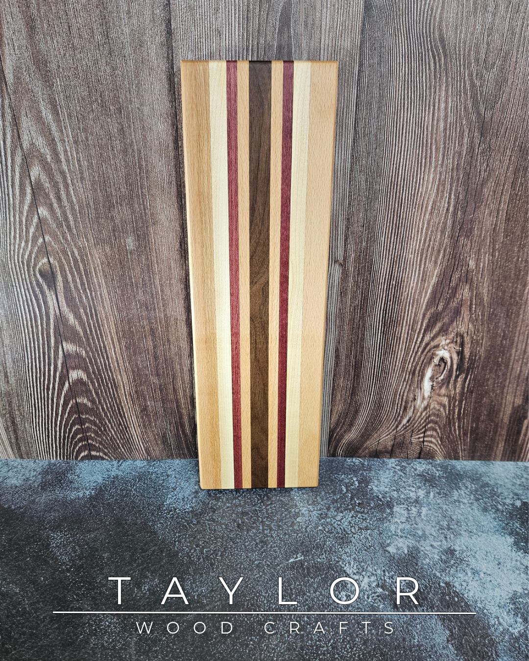 Wooden cutting board with multicolored stripes on a wooden surface, branded 'Taylor Wood Crafts'.