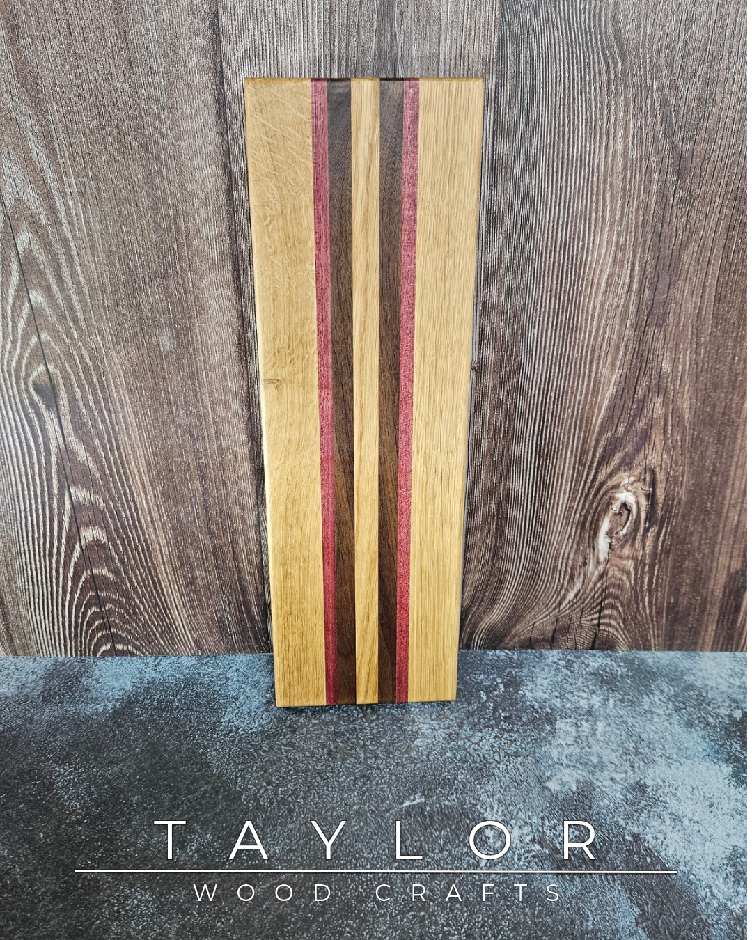Wooden cutting board with red and brown stripes on a wooden surface, branded 'Taylor Wood Crafts'.