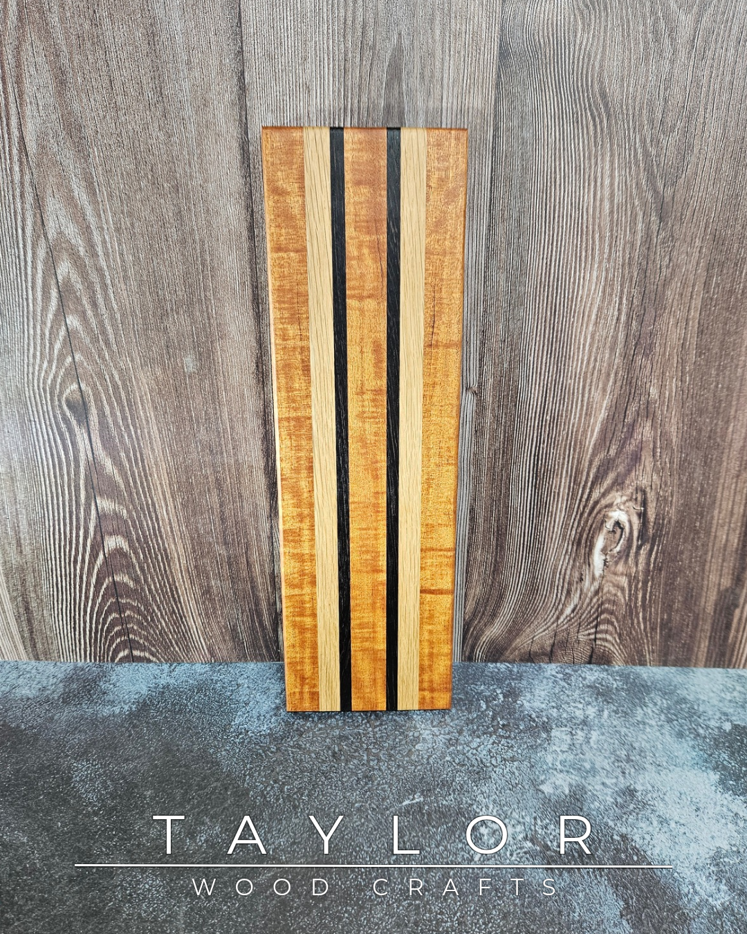 Wooden cutting board with striped pattern on a wooden surface, featuring the brand 'Taylor Wood Craft'.