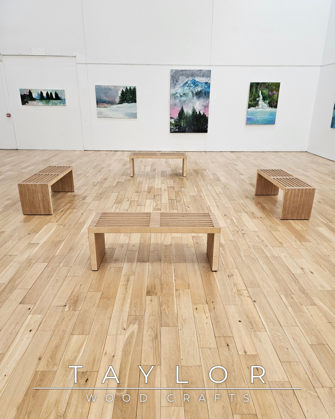 Wooden benches and tables arranged in a room with white walls and large windows, featuring the Taylor Wood Crafts logo.
