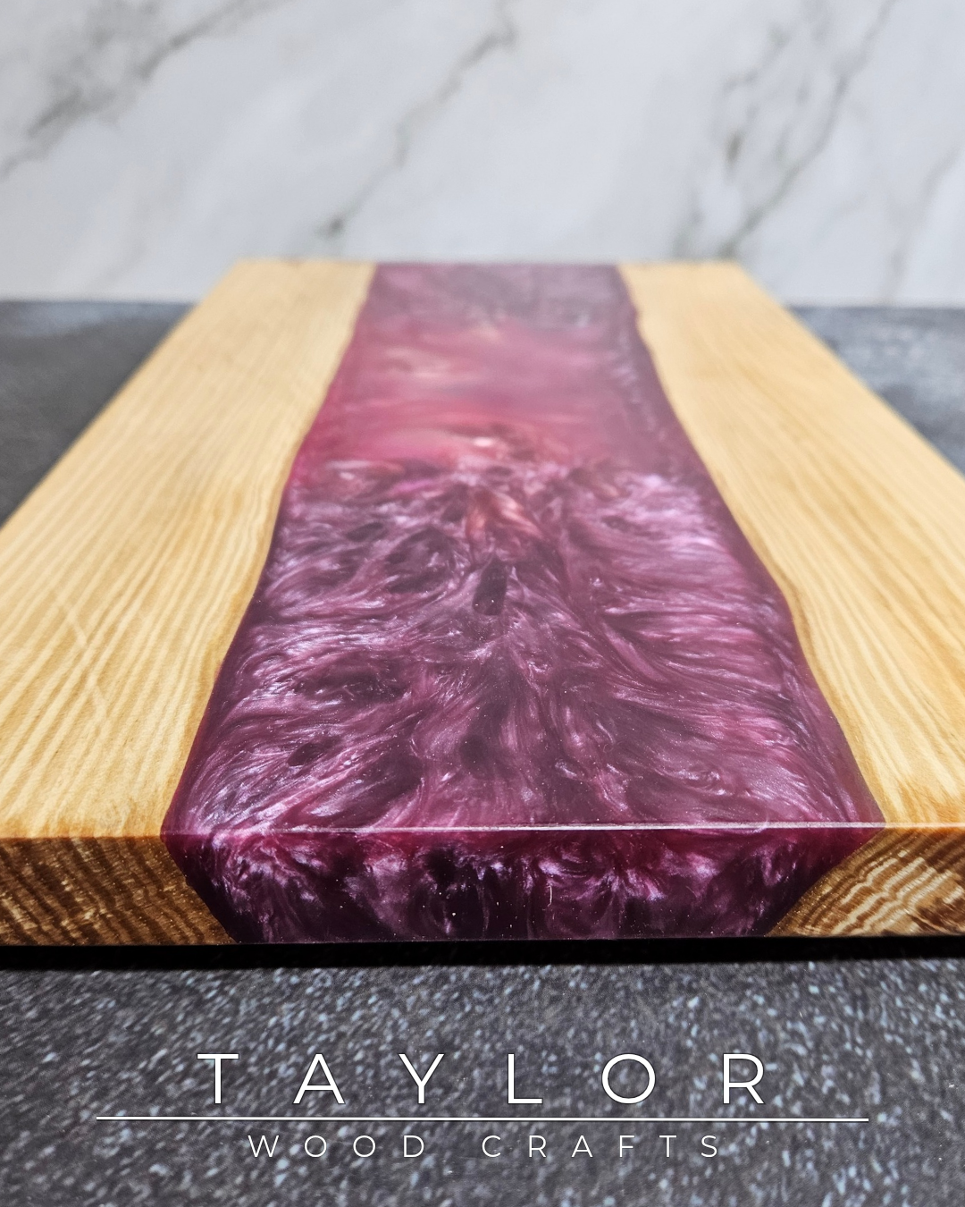 Wooden cutting board with purple resin inlay on a gray surface, branded 'Taylor Wood Crafts'.