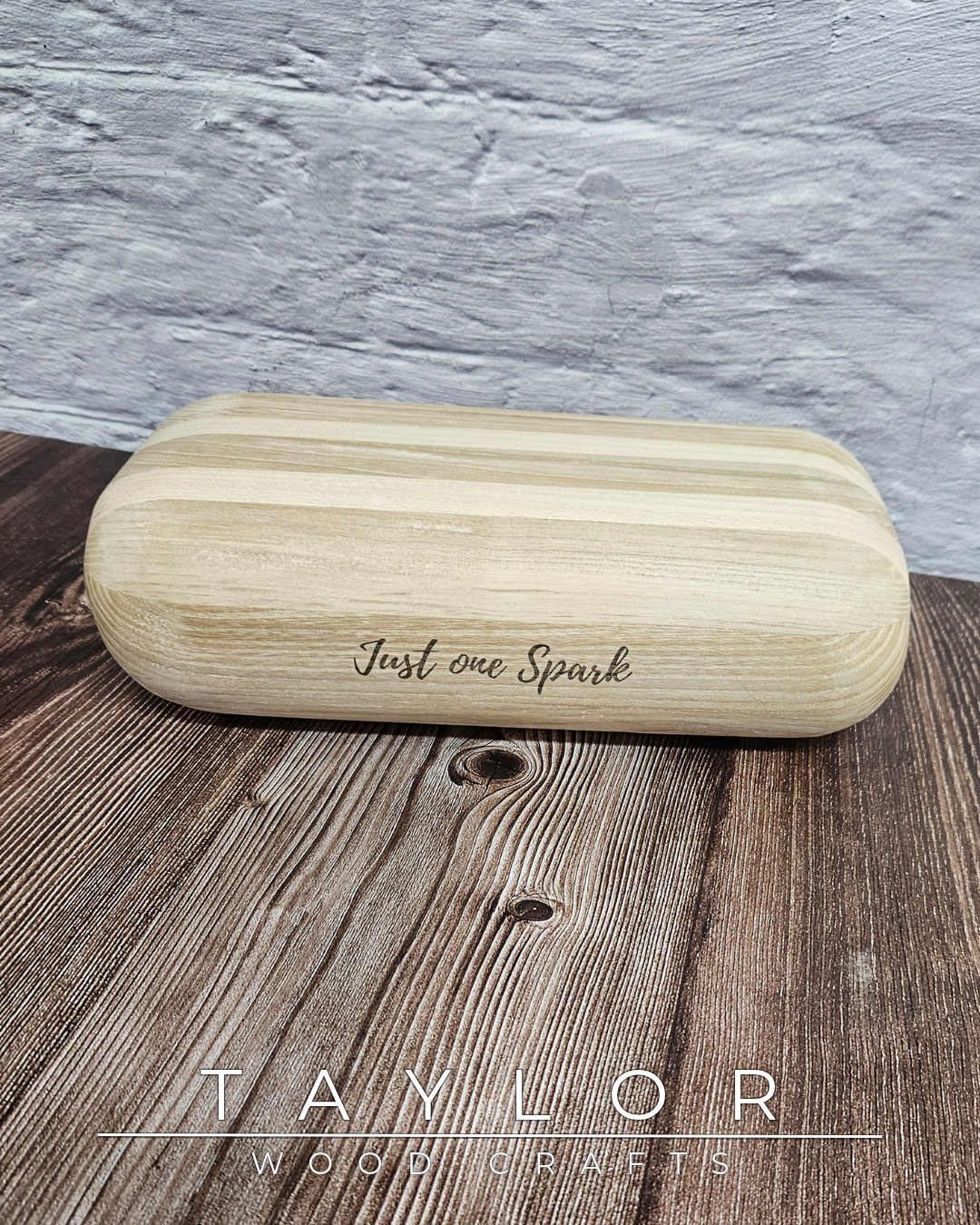 Wooden glasses case with 'Just one Spark' engraving on a wooden surface, branded 'Taylor Wood'.