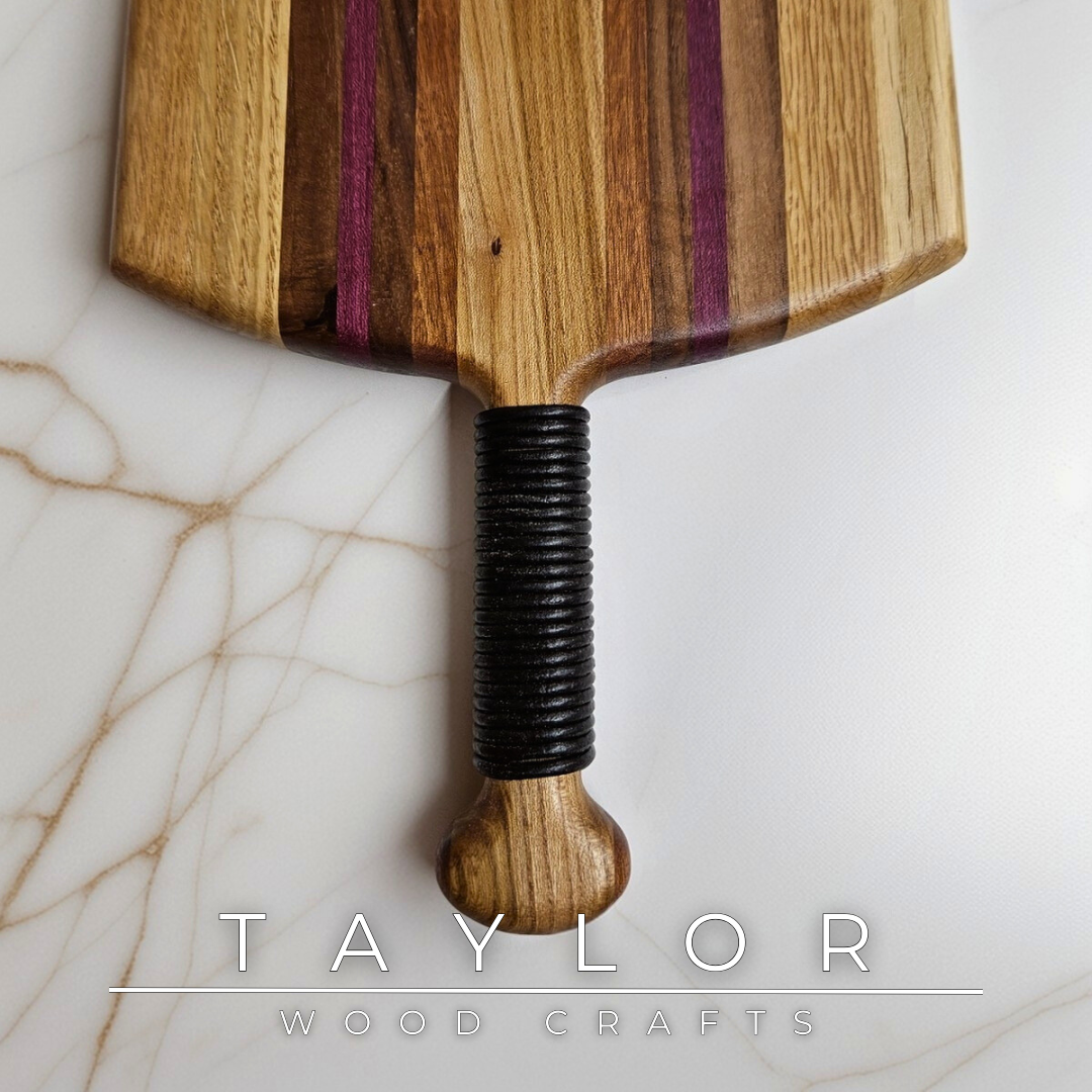 Unique charcuterie board by Taylor Wood Crafts, made from mixed hardwoods with a leather-wrapped handle.