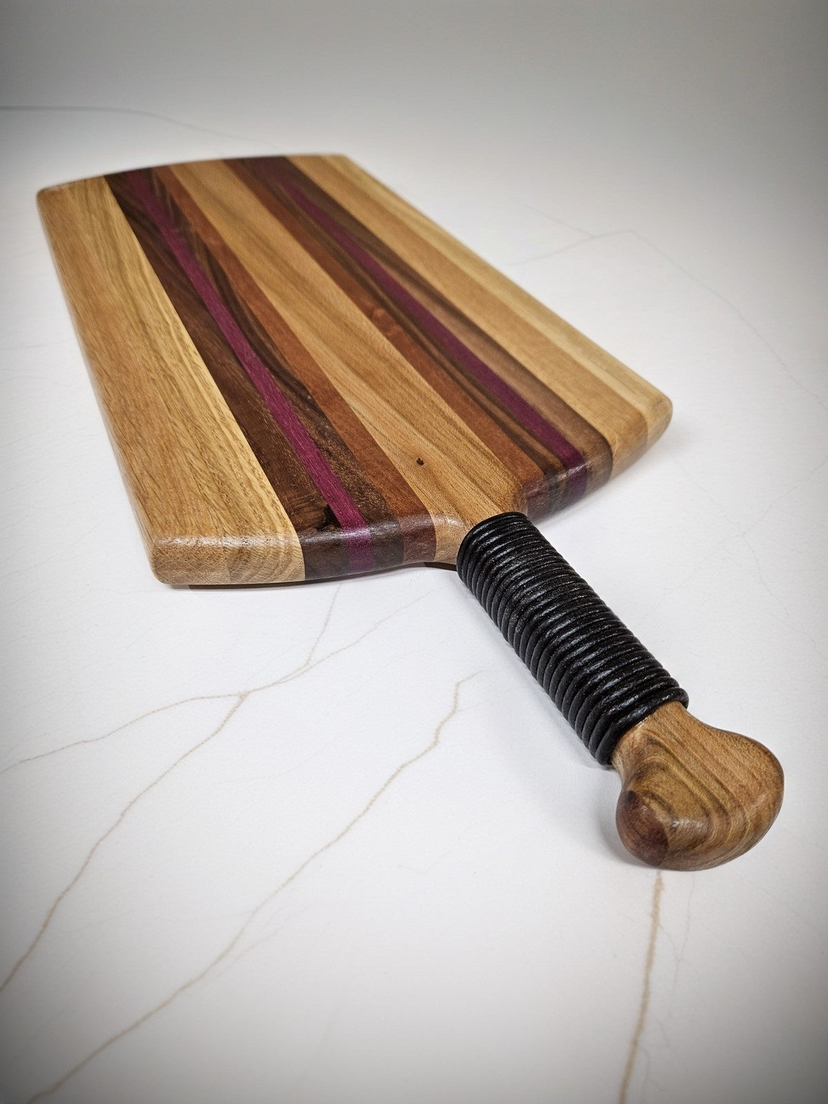 Unique charcuterie board by Taylor Wood Crafts, made from mixed hardwoods with a leather-wrapped handle.